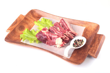 Raw beef edges, lettuce leaf and spices on wooden desk isolated on white background from above and copy space. ready for cooking.