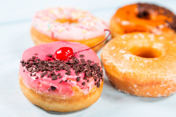 Different donuts on light blue background. Close up image with selective focus
