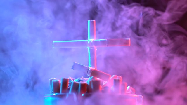 Smoldering cross of cigarettes in an ashtray. Slow motion