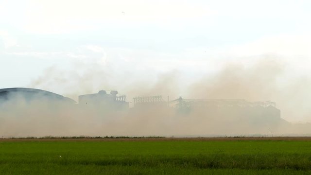 Dark smoke from burn of straw is cover industry plant, air pollution impact on the environment.