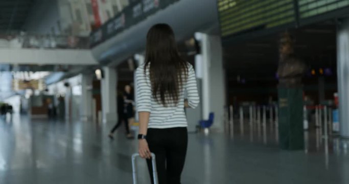 Young lady with black hair carries suitcase