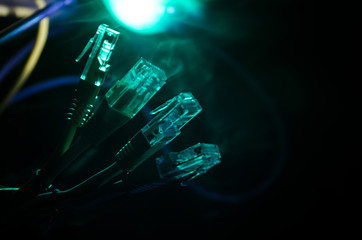 Obraz na płótnie Canvas Network switch and ethernet cables, symbol of global communications. Colored network cables on dark background with lights and smoke. Selective focus