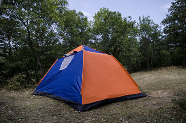 Camping and tent near the forest in could sky, Mountains of Caucasus Azerbaijan. Orange blue tent