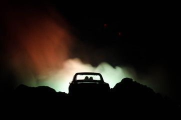 Plakat silhouette of car with couple inside on dark background with lights and smoke. Romantic scene. Love concept