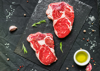 Fototapeta na wymiar Rib eye beef cow steak meat with spices and herbs against black background