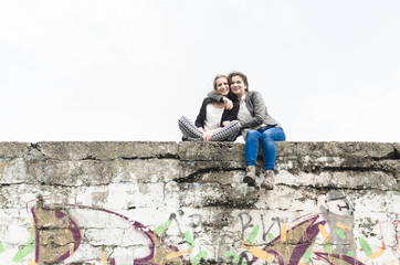 Fototapeta na wymiar Two girls sit on a large wall