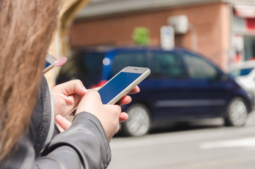 Women hand in the city typing message on mobile phone