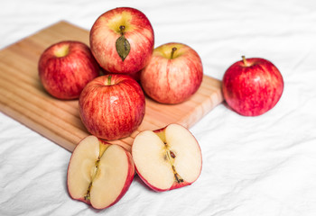 Red and pink apples on a wooden board against white background