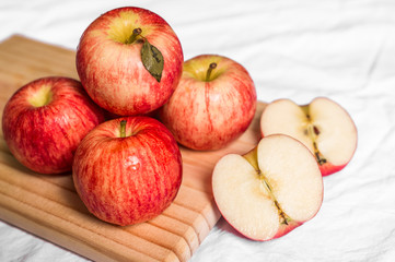 Red and pink apples on a wooden board against white background