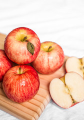 Red and pink apples on a wooden board against white background