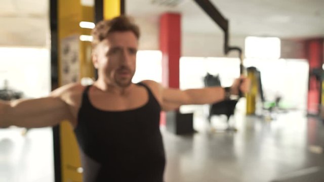 Middle-aged fit male doing pectoral fly workout in gym, training his arm muscles