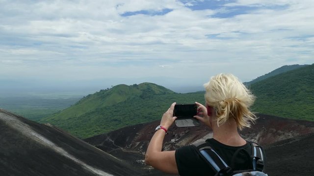 European woman takes pictures with mobile from Cerro Negro vulcano