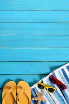 Summer beach background border striped towel sunglasses and starfish on old weathered blue wood deck decking for vacation holiday photo vertical