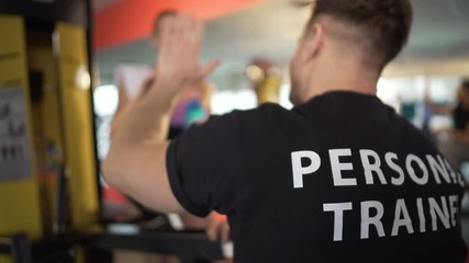 Personal trainer communicating with female client, giving high five, teamwork
