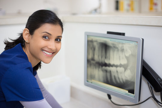 Closeup Portrait Of Allied Health Dental Professional In Blue Scrubs Examining Dental X-ray On Computer Screen, Isolated Dentist Office