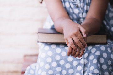 Little girl hands folded  on a book in vintage color tone