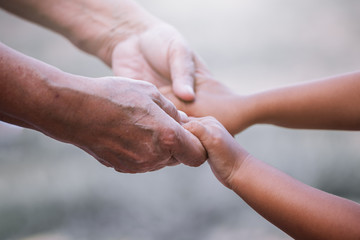Grandmother and child little girl holding hand together with love in vintage color tone