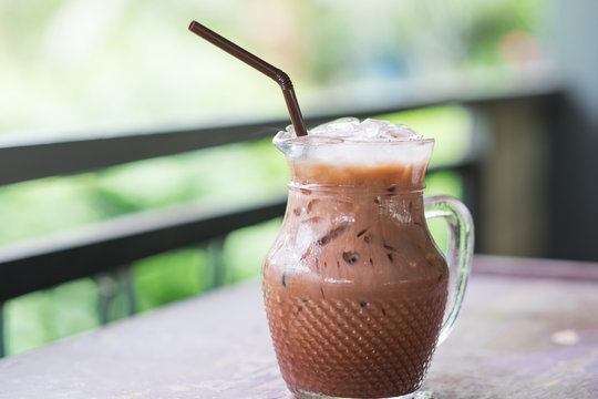 iced cocoa in glass pitcher putting on table. have blurred nature background. this image for food and beverage concept