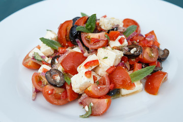 Vegetable salad with feta cheese on white plate