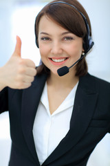 Beautiful woman working at callcenter, using headset showing thu