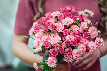 woman in a dress holding wedding bouquets of biege carnations and pink roses