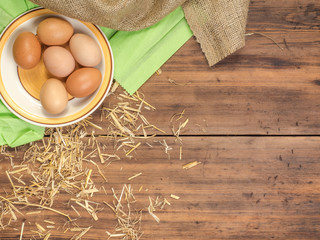 Rural eco background with brown chicken eggs, a piece of burlap and straw on the background of old wooden planks. The view from the top. Creative background for Easter cards or menu