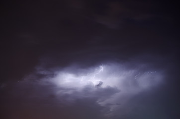Fototapeta na wymiar Thunderstorm Lightnings Behind The Clouds In The Night Sky 