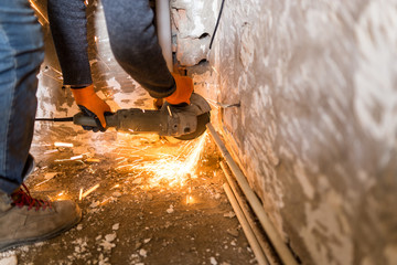 Worker cuts a metal pipe with sparks