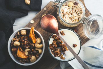Yoghurt, muesli, nuts and dried fruits on a wooden Board over dark stone background. Diet, weight loss or healthy eating concept. Copy space for text or design