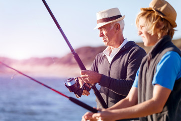 Obraz premium Senior man fishing with his grandson