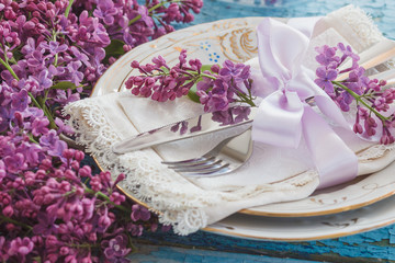 Tableware and silverware with violet lilac on the wooden backgro