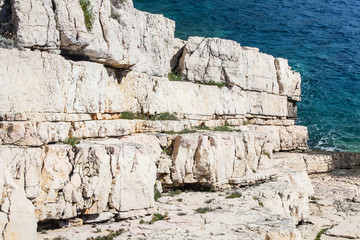 Beautiful white rock ocean coast as geology stone layers going in to the blue sea as background full of bright sunlight on a summer day