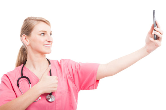 Nurse wearing scrubs taking selfie with smartphone showing like