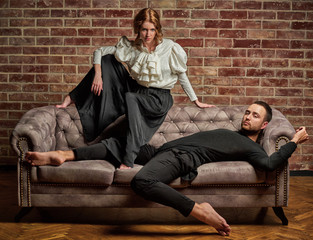 Female ballet dancer and male latin dancer in contemporary style in pose lie on the sofa