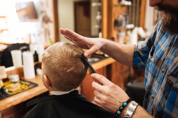 Professional nice barber touching the top of the boys head