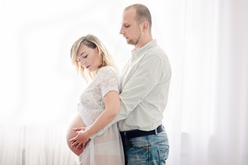 Young pregnant woman and her husband are hugging