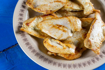 Fried chicken breasts on the plate above blue wooden planks board