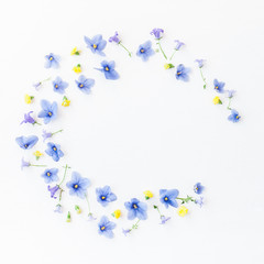 Wreath made of bellflower, pansy flowers and yellow flowers on white background. Flat lay, top view