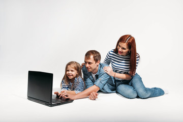 Happy family Father, mother and child lying on the floor with laptop on white background isolated