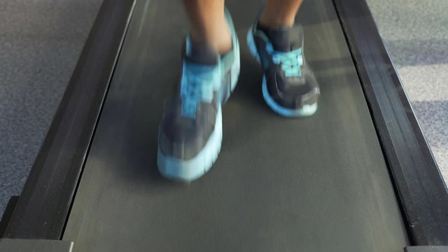 Legs of athletic male running on treadmill, cardio workout in the fitness club