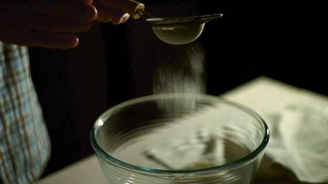 Man hand take sifts flour into glass bowl. Sifting flour through sieve. Pour flour into bowl. Powder flour in glass bowl. Preparation ingredients for baking. Culinary ingredients