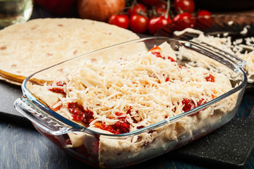 Traditional mexican enchiladas with chicken meat, spicy tomato sauce and cheese in heat resistant dish