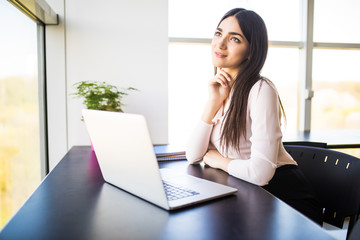 Portrait of businesswoman in sweater sitting at her workplace in office