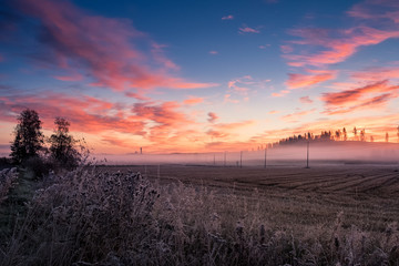 Scenic landscape with road and colorful sunrise at  foggy autumn morning in Finland.