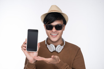 Smart casual asian man seated on chair, showing smartphone screen in studio background