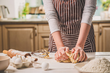 Woman hands kneading dough on kitchen table