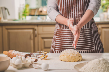 Woman slap his hands above dough closeup. Baker finishing his bakery, shake flour from his hands,...