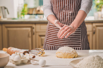 Woman slap his hands above dough closeup. Baker finishing his bakery, shake flour from his hands,...