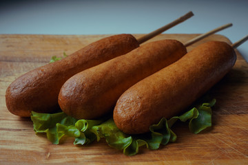 Traditional American food corn dogs on a lettuce leaf. fast food.