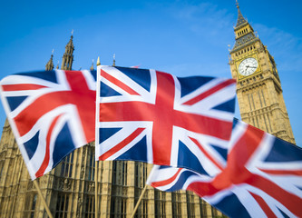Fototapeta na wymiar Great British Union Jack flag sflying in motion blur in front of Big Ben and the Houses of Parliament at Westminster Palace, London, UK